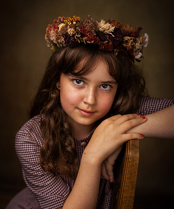 junges Mädchen mit braunen Haaren mit Blumenkranz auf dem Kopf im Vintagestil